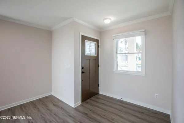 a view of an empty room with wooden floor and a window
