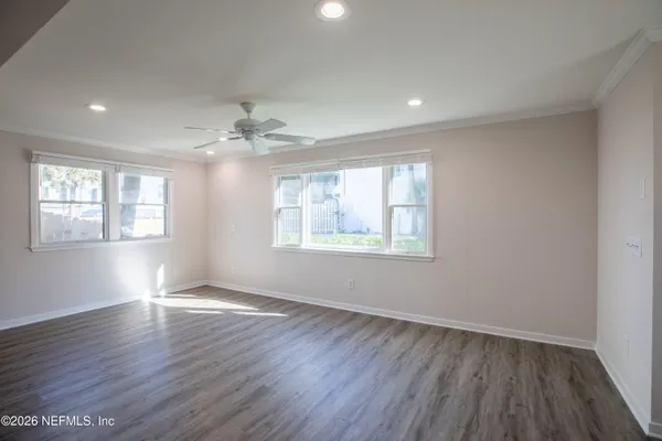 a view of an empty room with wooden floor and a window