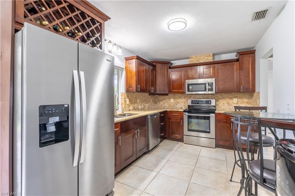 2100 55th Street Southwest Naples, FL 34116 - Photo 23 of 50 a kitchen with granite countertop a refrigerator and a stove top oven