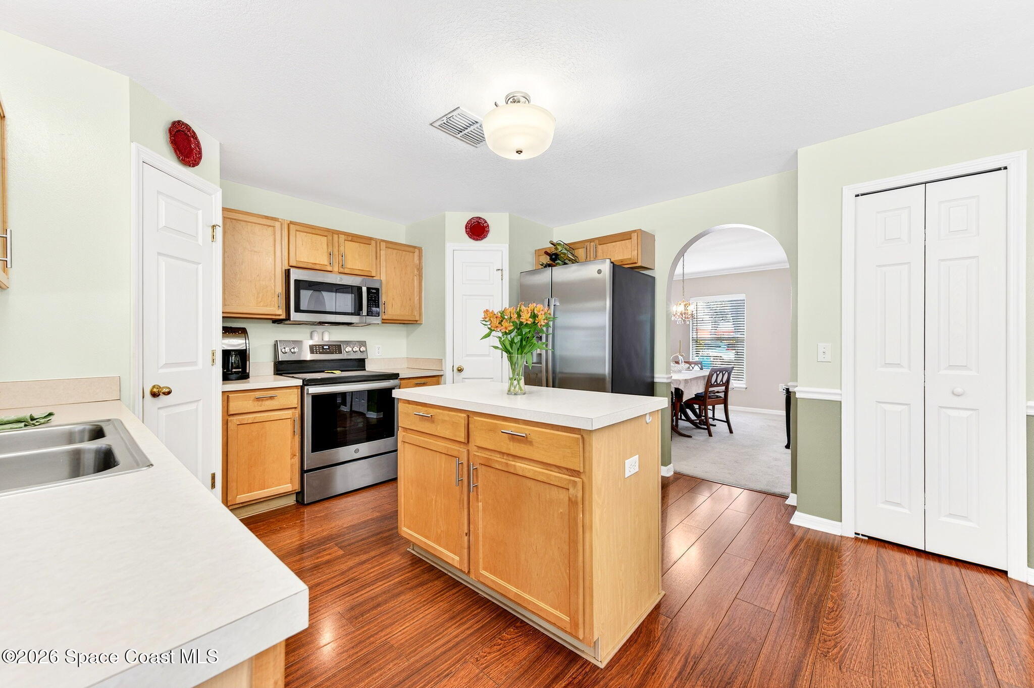 2186 Spring Creek Circle Palm Bay, FL 32905 - Photo 10 of 40 a kitchen with a refrigerator a stove top oven a sink dishwasher and white cabinets with wooden floor