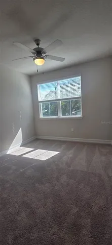 an empty room with windows and ceiling fan