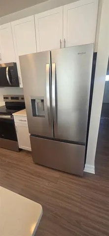 a view of a refrigerator in kitchen and an empty room