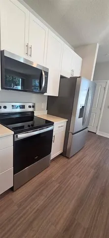 a kitchen with stainless steel appliances wooden cabinets and wooden floor