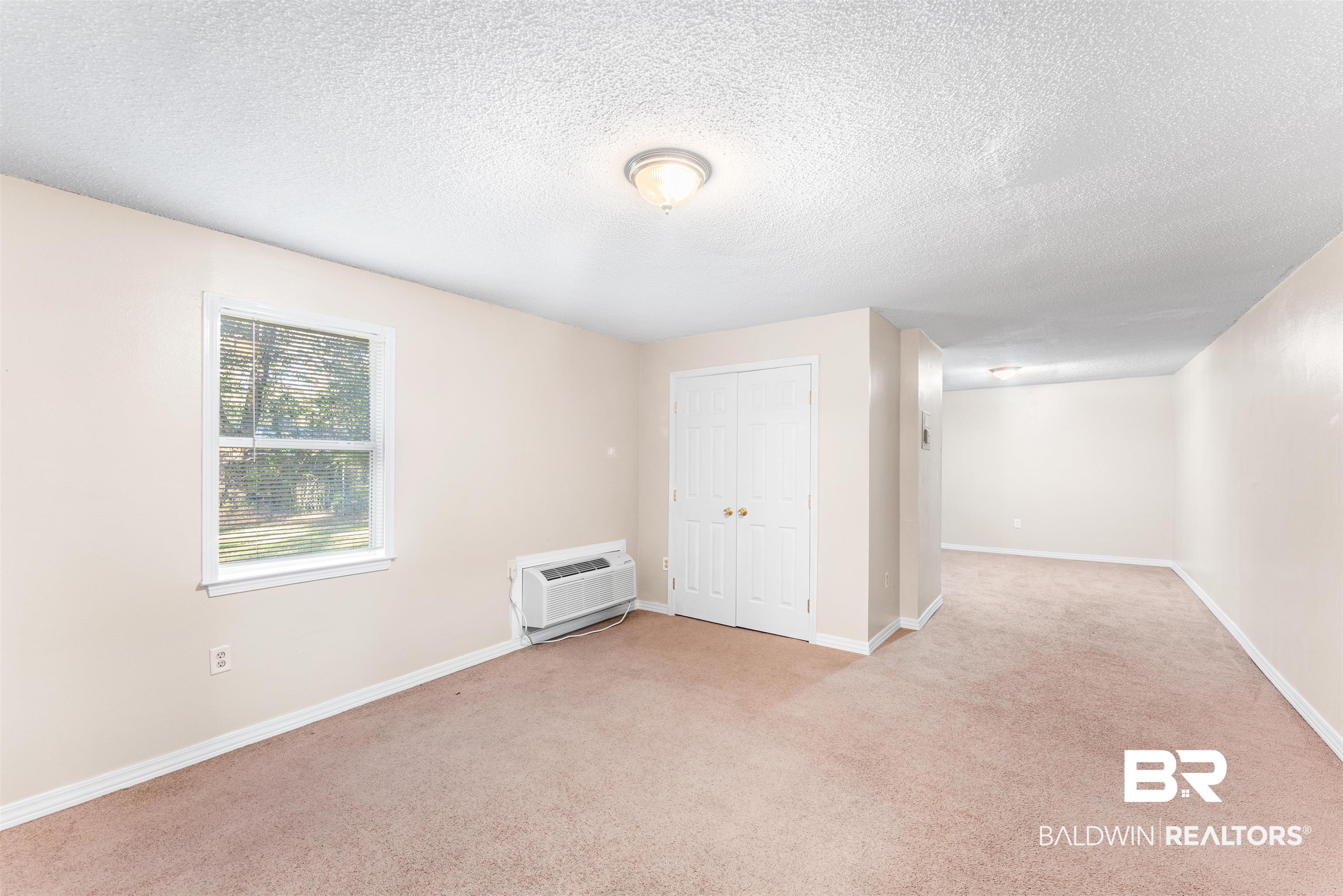 5551 Springer Court Theodore, AL 36582 - Photo 27 of 37 Unfurnished room with a textured ceiling, light carpet, and a wall mounted air conditioner