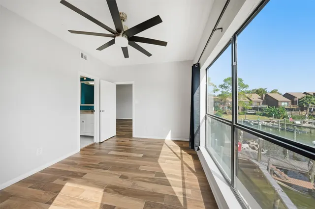 a view of empty room with wooden floor and fan