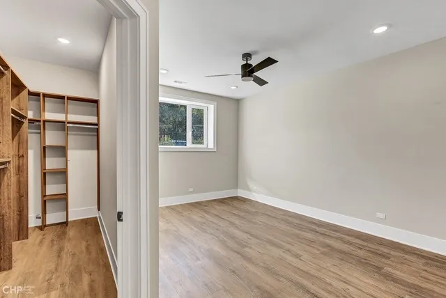 a view of empty room with wooden floor and fan