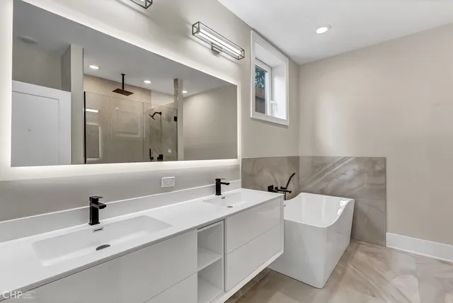 a bathroom with a double vanity sink mirror and bathtub