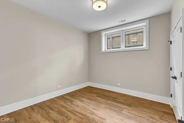 a view of an empty room with closet and wooden floor