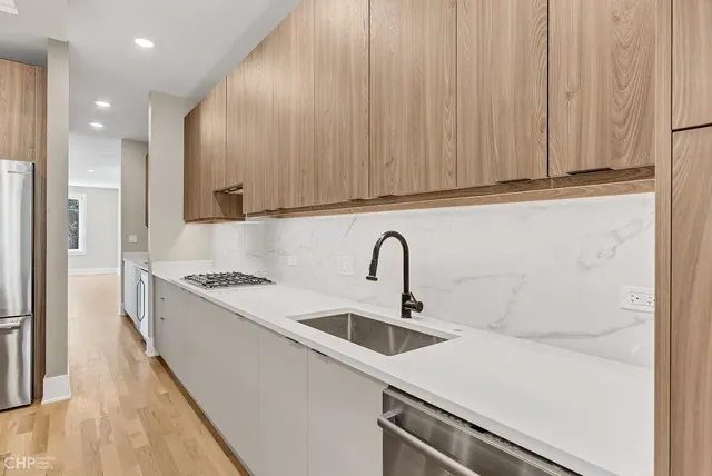 a large kitchen with stainless steel appliances kitchen island a large counter top and a wooden floors