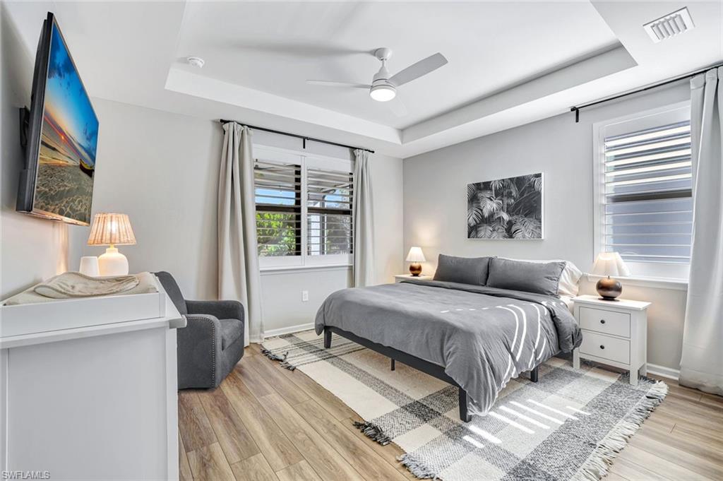 2240 Yellowfin Circle Naples, FL 34114 - Photo 11 of 38 Master Bedroom featuring a tray ceiling, plantation shutters, luxury vinyl style floors, impact windows and a ceiling fan