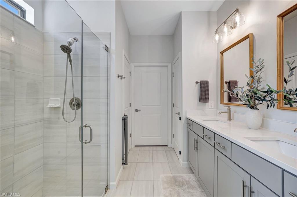 2240 Yellowfin Circle Naples, FL 34114 - Photo 13 of 38 Master bathroom with a tiled shower and double vanity
