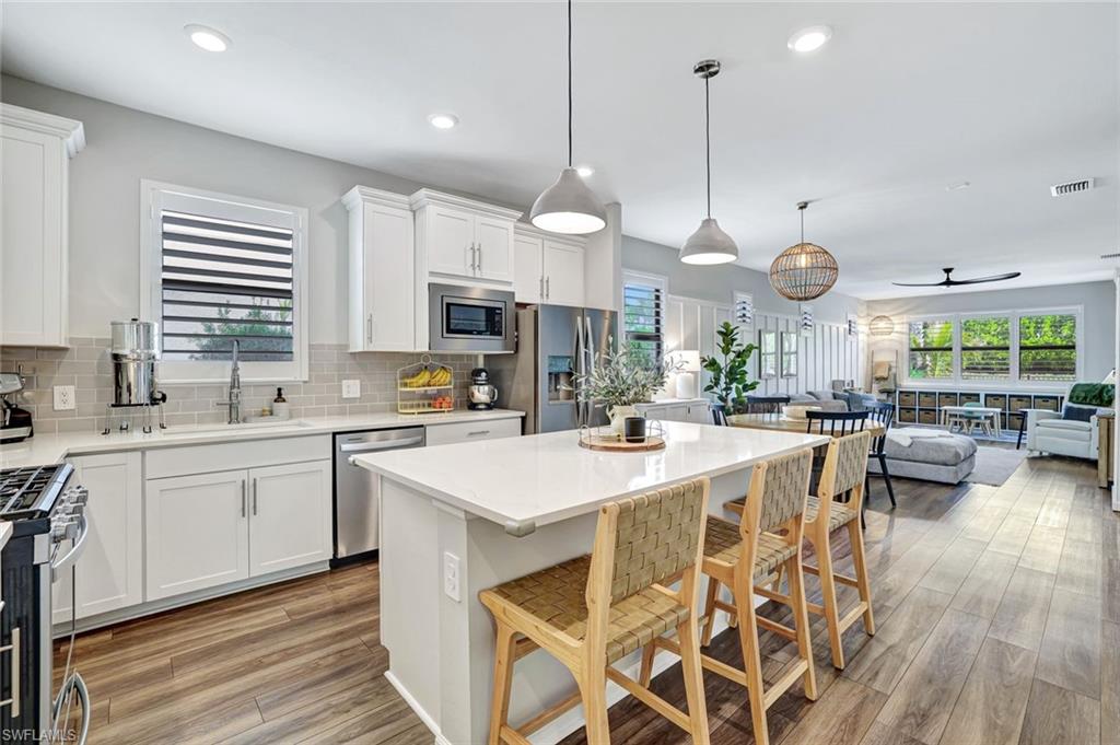 2240 Yellowfin Circle Naples, FL 34114 - Photo 37 of 38 Kitchen with a breakfast bar, white cabinets, stainless steel appliances, open floor plan, and pendant lighting