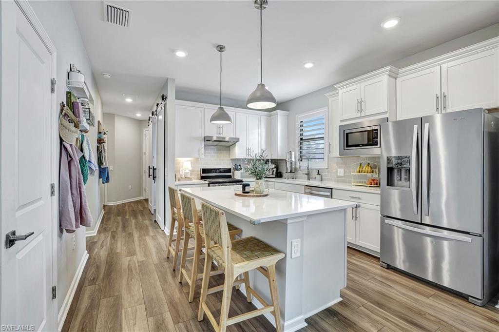 2240 Yellowfin Circle Naples, FL 34114 - Photo 4 of 38 Kitchen featuring stainless steel appliances, white cabinets and pendant lighting, and a kitchen island