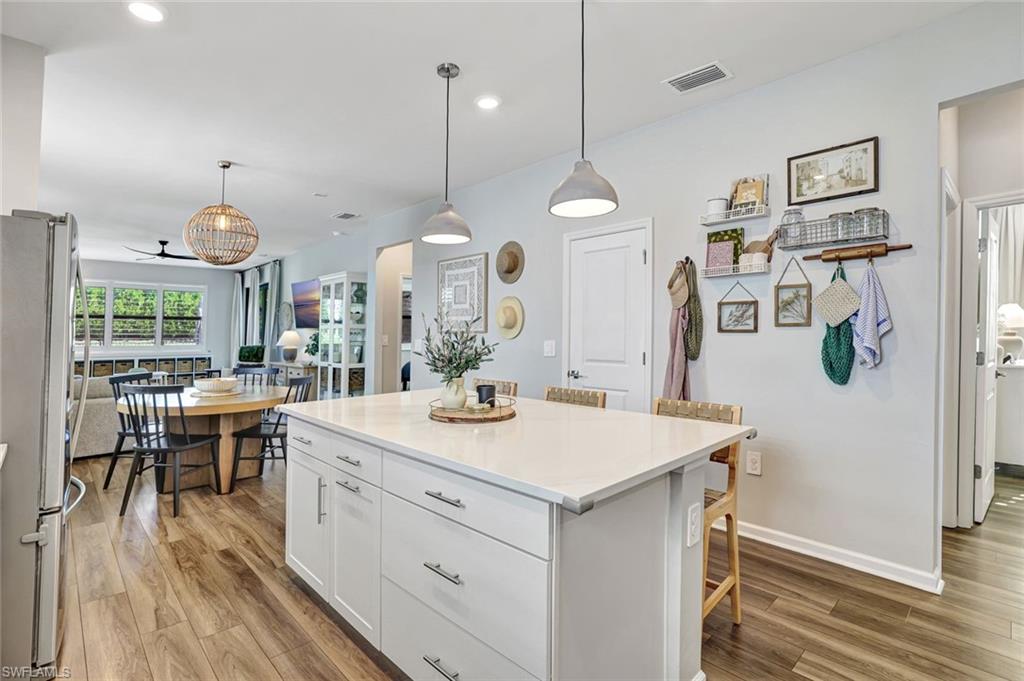 2240 Yellowfin Circle Naples, FL 34114 - Photo 5 of 38 Kitchen featuring white cabinetry, pendant lighting, freestanding refrigerator, a kitchen bar, and a center island