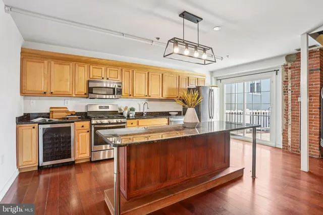 a kitchen with stainless steel appliances granite countertop a stove and chairs with wooden floor