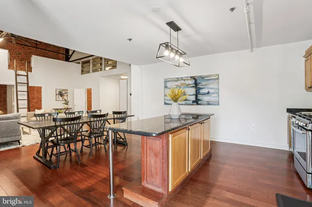 a kitchen with stainless steel appliances granite countertop a refrigerator a sink dishwasher a stove and white countertops with wooden floor