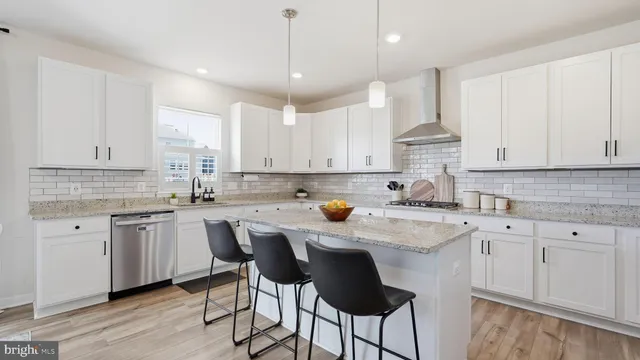 a kitchen with stainless steel appliances granite countertop a sink a stove a refrigerator and white cabinets