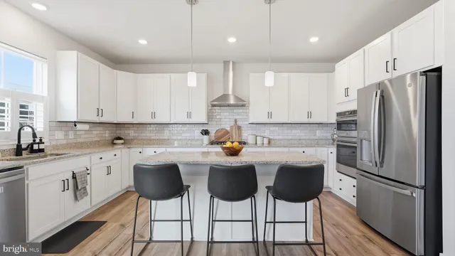 a kitchen with stainless steel appliances granite countertop a dining table chairs refrigerator and cabinets