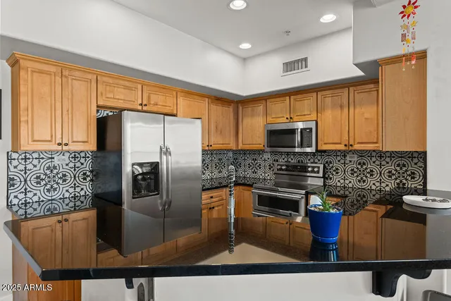 a kitchen with stainless steel appliances granite countertop a refrigerator a stove top oven a sink and dishwasher