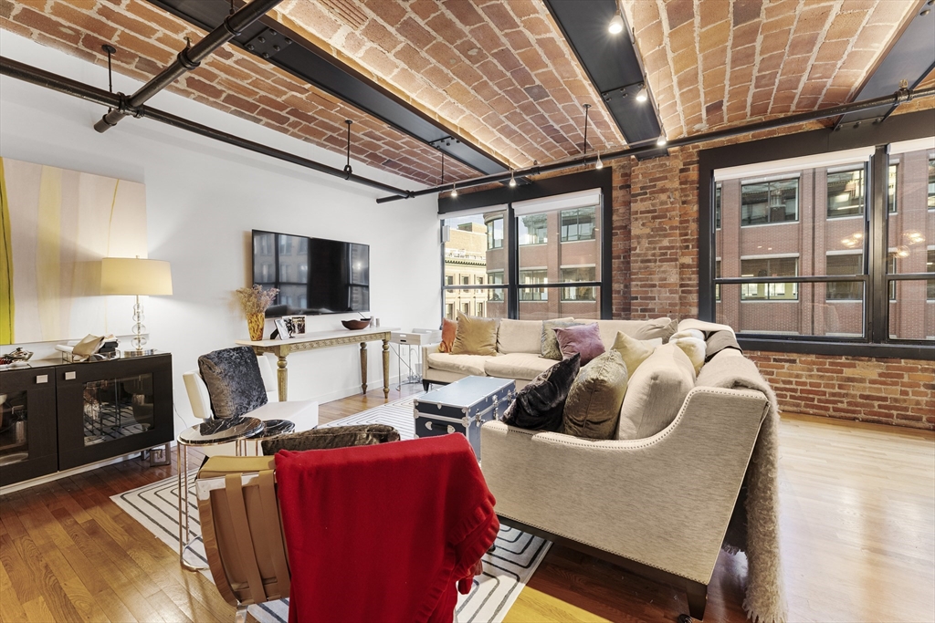 121 Beach Boston Ma, Unit 502 Boston, MA 02111 - Photo 2 of 21 a living room with furniture a flat screen tv and a floor to ceiling window