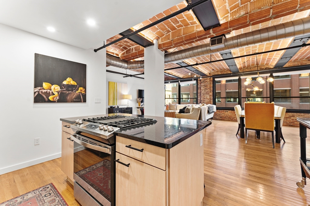 121 Beach Boston Ma, Unit 502 Boston, MA 02111 - Photo 6 of 21 a kitchen with stainless steel appliances granite countertop a stove and a view of living room