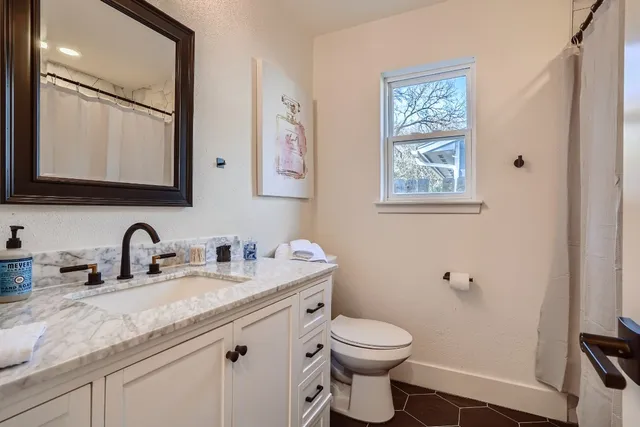 a bathroom with a granite countertop toilet sink and mirror
