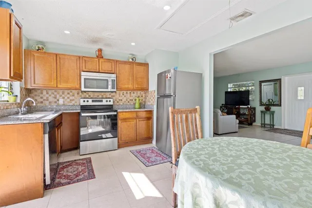 a kitchen with stainless steel appliances kitchen island granite countertop a refrigerator a stove a sink dishwasher with a dining table and chairs