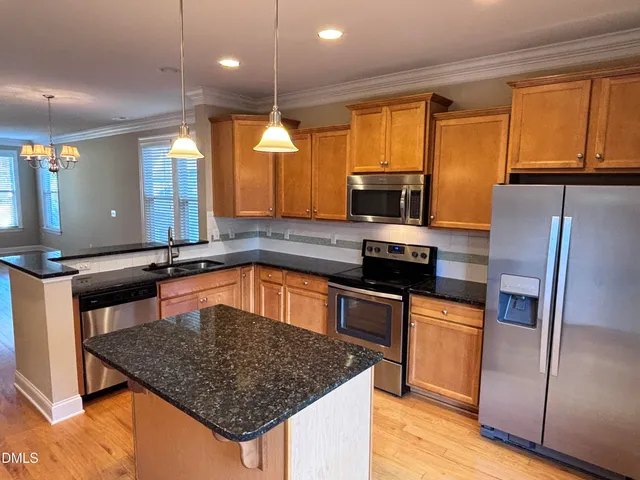 a kitchen with stainless steel appliances granite countertop a sink a stove and a refrigerator