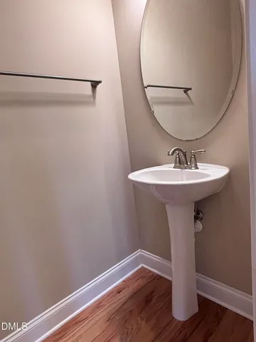 a bathroom with a sink a mirror and wooden floor