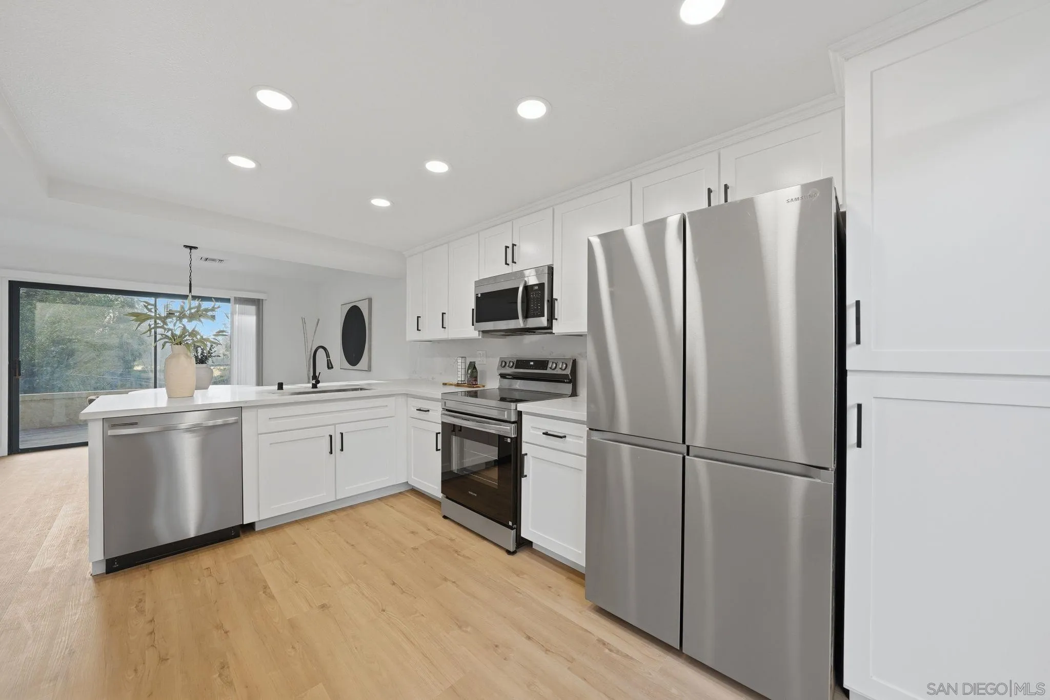 10450 Ridgewater Lane San Diego, CA 92131 - Photo 7 of 47 a kitchen with a refrigerator stainless steel appliances wooden floor and window