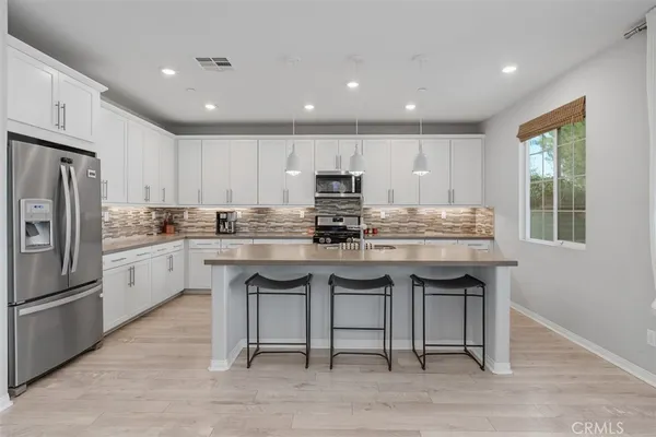 a kitchen with stainless steel appliances granite countertop a table chairs sink refrigerator and microwave