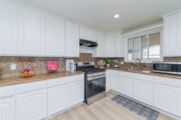 a kitchen with granite countertop white cabinets and white appliances