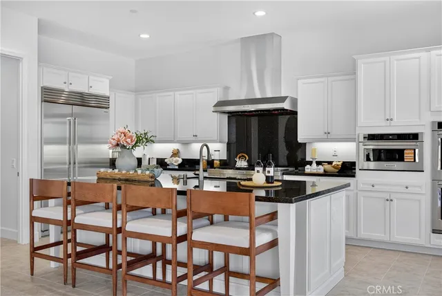 a kitchen with stainless steel appliances a dining table chairs refrigerator and sink