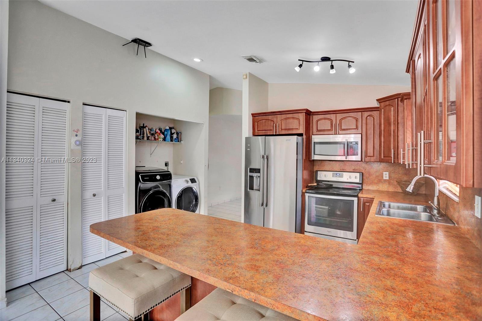 2574 West 71st Place Hialeah, FL 33016 - Photo 26 of 48 a kitchen with stainless steel appliances kitchen island granite countertop a refrigerator a stove and a sink with granite countertops