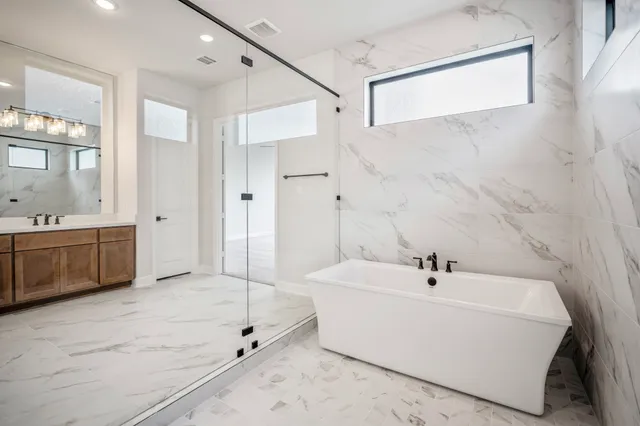 a bathroom with a double vanity sink a mirror a bathtub and shower