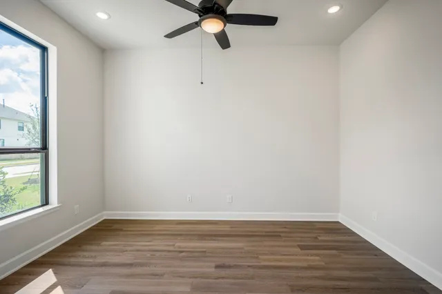 a view of an empty room with window and wooden floor