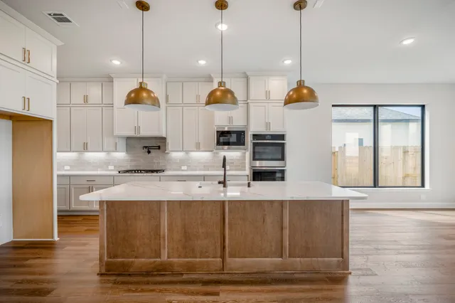 a kitchen with kitchen island granite countertop a stove a sink a center island and wooden floor