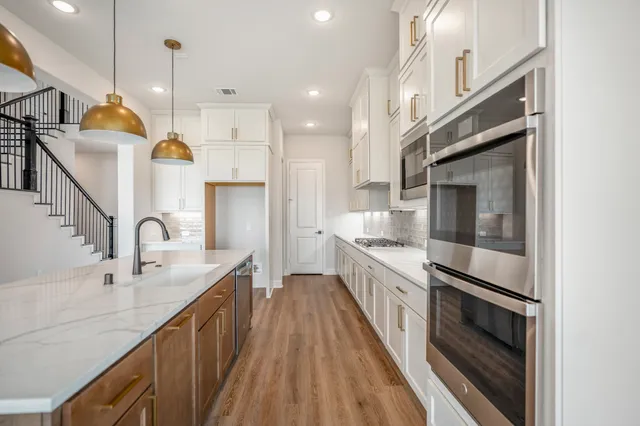a kitchen with a sink a wooden floor a clock and a chandelier
