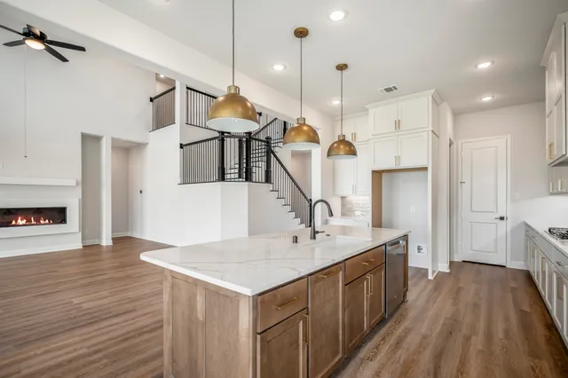 a open kitchen with a refrigerator a sink dishwasher a dining table and chairs with wooden floor