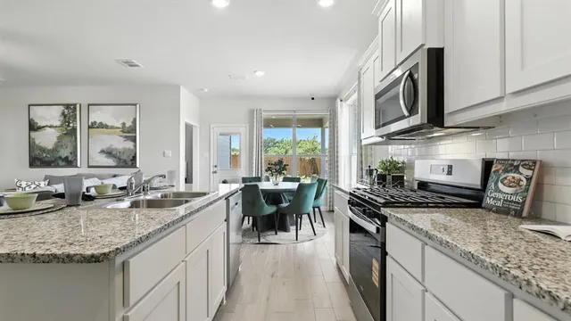 a kitchen with stainless steel appliances granite countertop a stove a sink a microwave a dining table and chairs