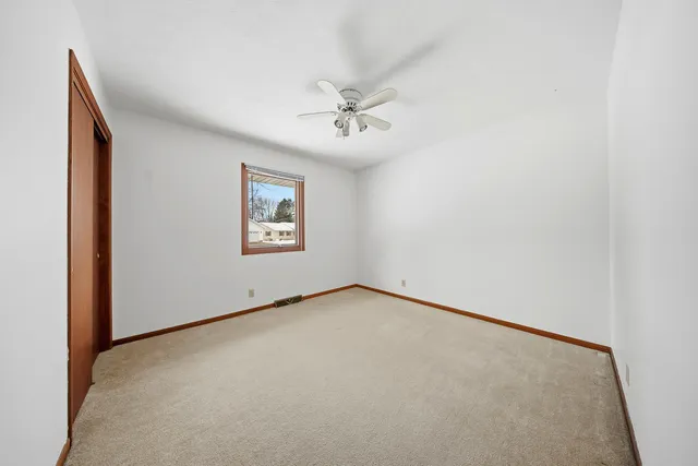 an empty room with windows and ceiling fan