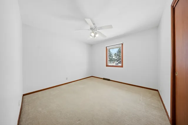 an empty room with windows and ceiling fan