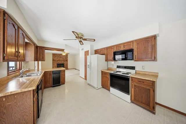 a kitchen with stainless steel appliances granite countertop a sink a stove top oven a chimney a refrigerator and black appliances