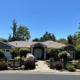 a front view of house with yard outdoor seating and trees in the background