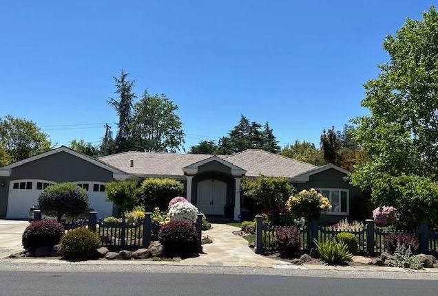a front view of house with yard outdoor seating and trees in the background