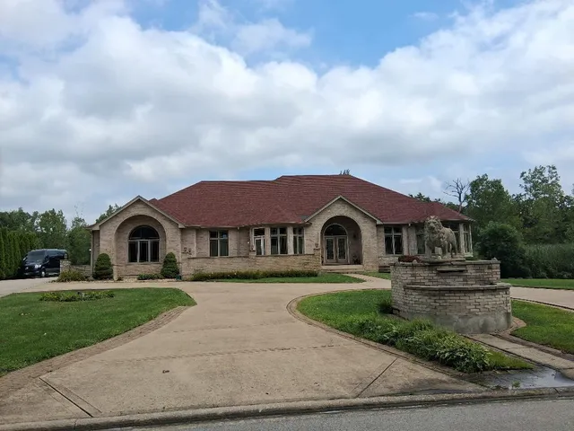 a front view of a house with a garden and trees