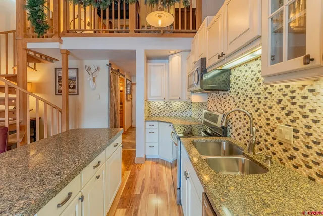 a kitchen with granite countertop a sink and a wooden floor
