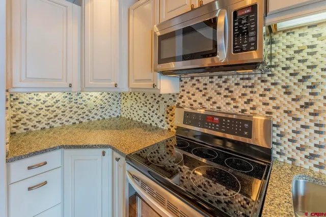 a kitchen with granite countertop a stove and a microwave