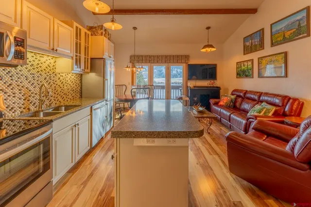 a open kitchen with stainless steel appliances granite countertop a stove and a wooden floors