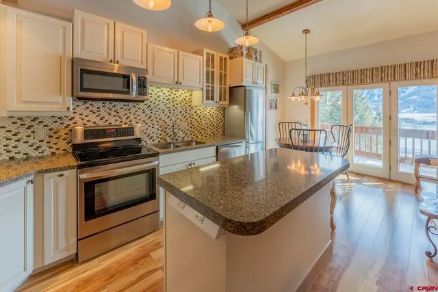 a kitchen with granite countertop a stove top oven a sink a counter space and cabinets